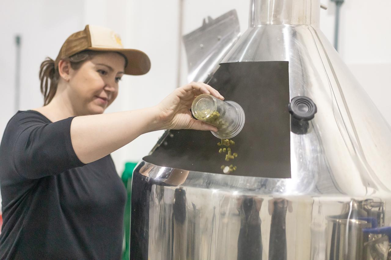 Proprietária colocando itens para fazer cerveja artesanal